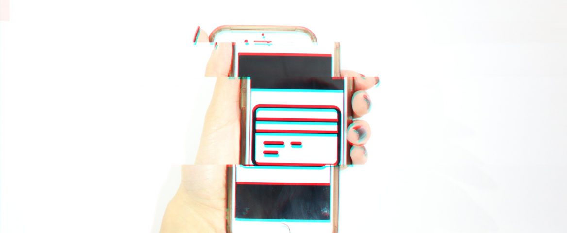 Uma mão segura um celular com uma foto com o ícone de um cartão de crédito. A imagem foi distorcida para gerar um efeito futurístico